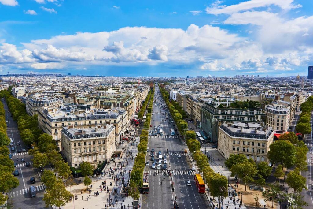 A captivating view of the Champs-Élysées adorned with bustling cafes, luxury shops, and the iconic Arc de Triomphe in the distance,